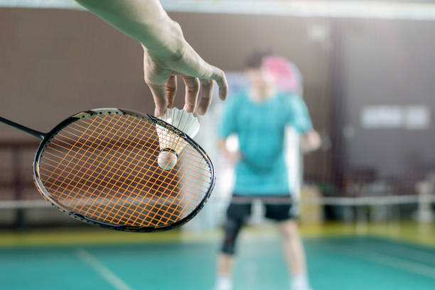 Player serving a shuttlecock in badminton.